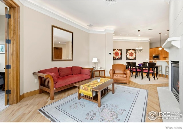 living room with crown molding, light hardwood / wood-style flooring, and a notable chandelier