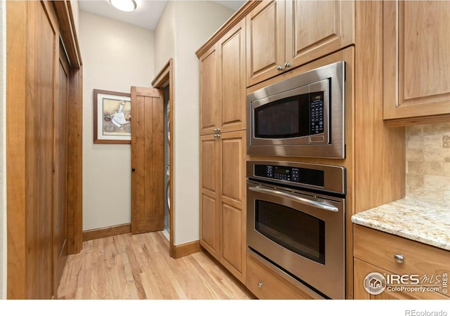 kitchen featuring light stone countertops, stainless steel appliances, decorative backsplash, and light hardwood / wood-style flooring