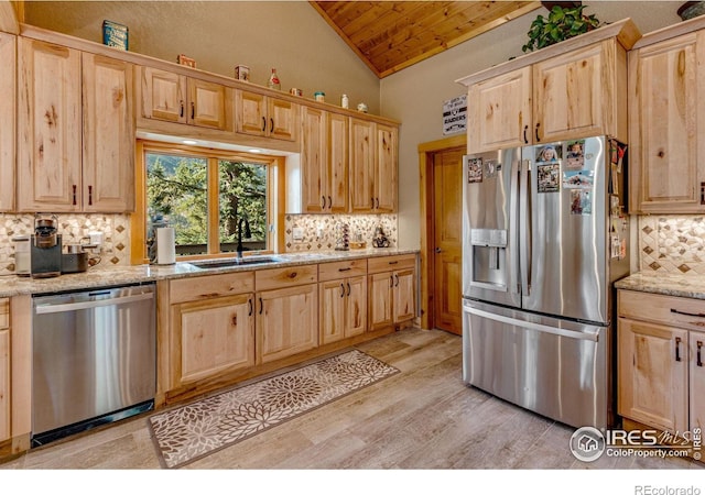 kitchen featuring light stone countertops, light hardwood / wood-style floors, stainless steel appliances, sink, and lofted ceiling