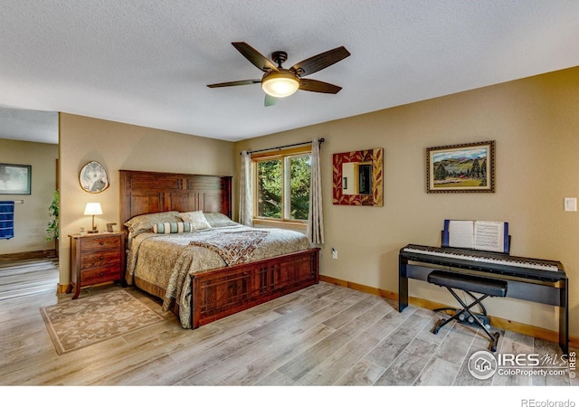 bedroom with a textured ceiling, ceiling fan, and light hardwood / wood-style floors