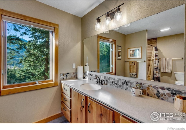 bathroom featuring a textured ceiling, vanity, toilet, and a shower with curtain