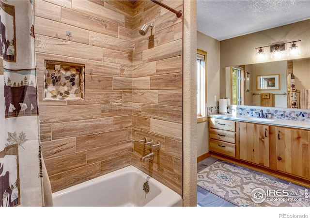 bathroom with tiled shower / bath combo, vanity, and a textured ceiling