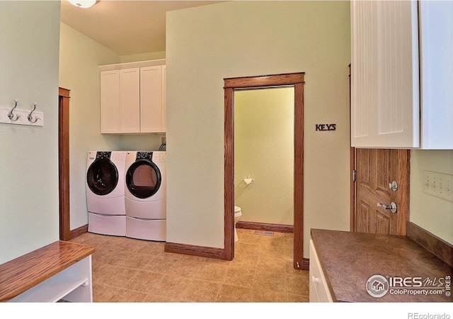 washroom with cabinets and washing machine and dryer