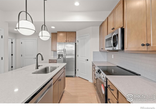 kitchen with appliances with stainless steel finishes, tasteful backsplash, sink, light hardwood / wood-style flooring, and hanging light fixtures