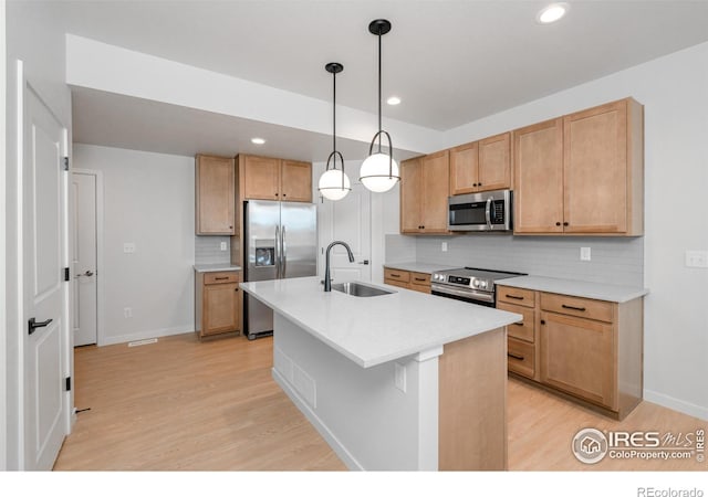 kitchen with pendant lighting, backsplash, sink, light wood-type flooring, and appliances with stainless steel finishes