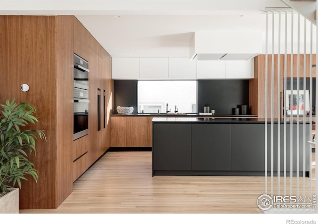 kitchen featuring light wood-type flooring, oven, and sink