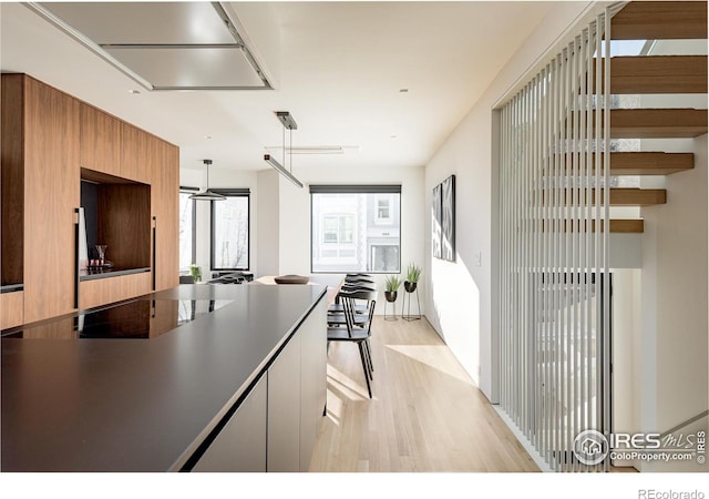 kitchen with a kitchen breakfast bar, hanging light fixtures, and light hardwood / wood-style floors