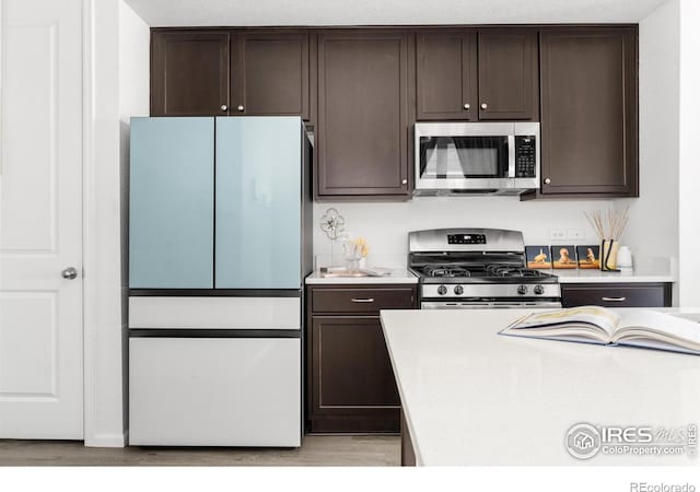 kitchen featuring dark brown cabinets, light wood-type flooring, and appliances with stainless steel finishes