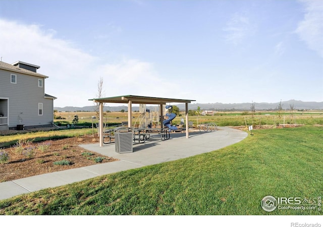 view of property's community featuring a lawn and a mountain view