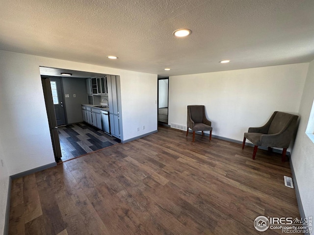 interior space with a textured ceiling, sink, and dark wood-type flooring