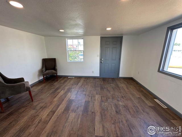 unfurnished room with a textured ceiling and dark wood-type flooring