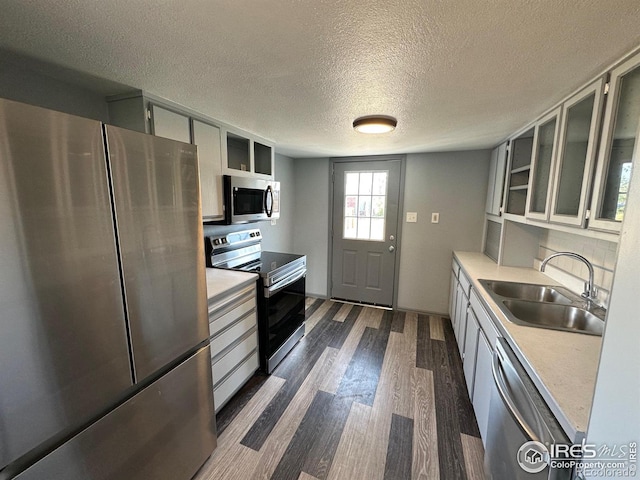 kitchen featuring a textured ceiling, dark wood-type flooring, sink, white cabinets, and stainless steel appliances