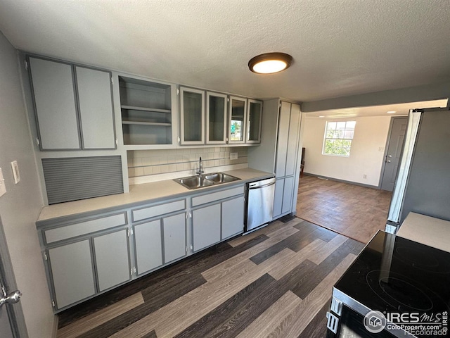 kitchen featuring dark wood-type flooring, tasteful backsplash, stainless steel appliances, a textured ceiling, and sink