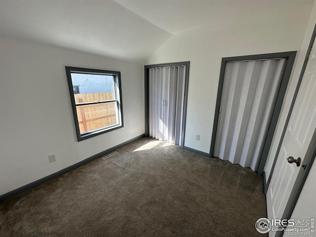 unfurnished bedroom featuring lofted ceiling and dark carpet