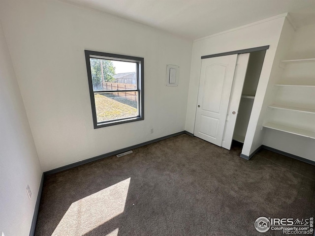 unfurnished bedroom featuring a closet and dark colored carpet