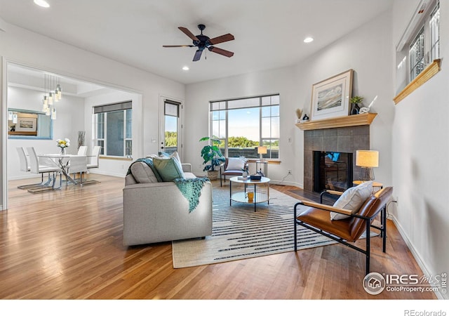 living room with a tile fireplace, ceiling fan, and hardwood / wood-style flooring