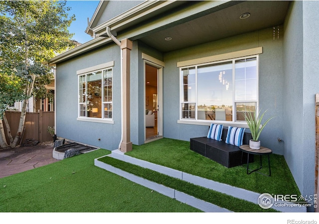 view of exterior entry featuring a lawn, outdoor lounge area, and a patio