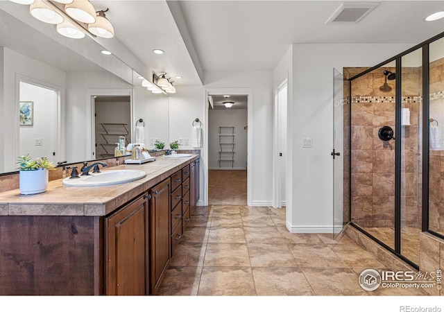 bathroom with walk in shower, vanity, and tile patterned floors