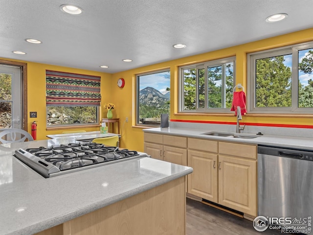 kitchen featuring a textured ceiling, sink, light brown cabinets, appliances with stainless steel finishes, and light stone countertops