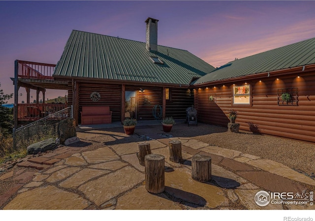 back house at dusk with a patio and a garage