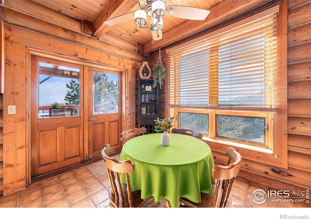 dining area featuring beamed ceiling, light tile patterned floors, rustic walls, ceiling fan, and wooden ceiling