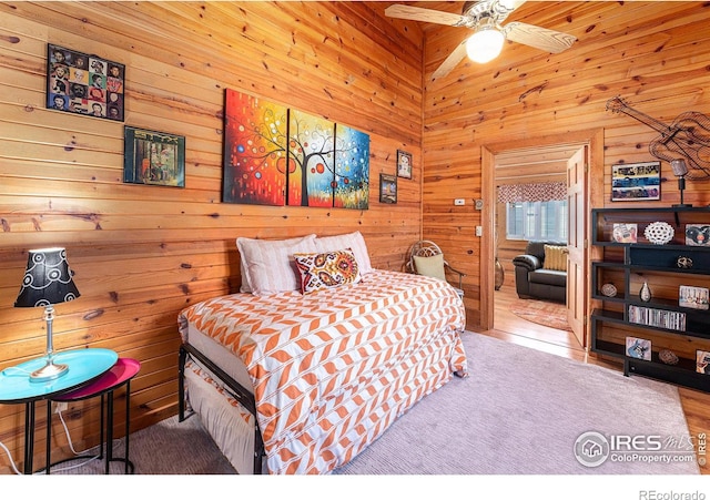 bedroom with wooden walls, ceiling fan, and wood-type flooring