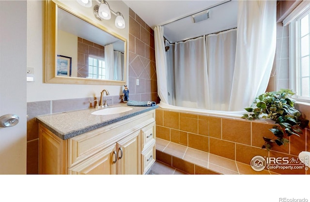 bathroom with vanity, plenty of natural light, tile walls, and shower / bath combo with shower curtain