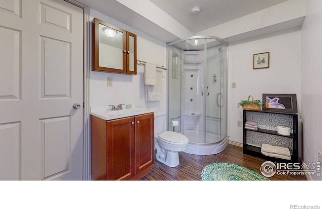 bathroom featuring walk in shower, wood-type flooring, toilet, and vanity