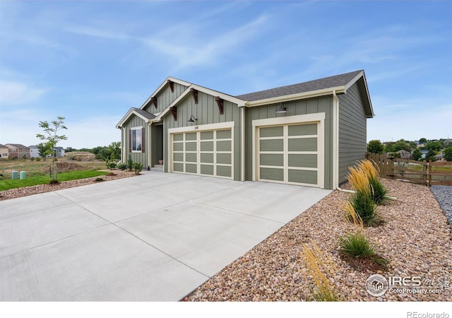 view of front of house featuring driveway, board and batten siding, an attached garage, and fence