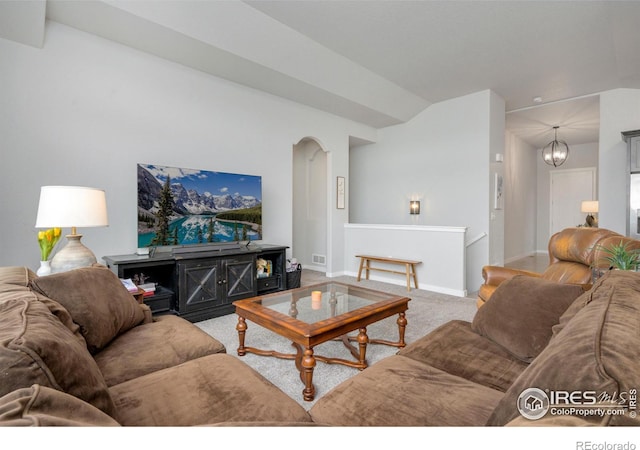 carpeted living area featuring baseboards, arched walkways, lofted ceiling, and a chandelier