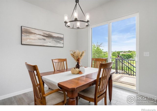 dining area with light wood-type flooring, baseboards, and a notable chandelier
