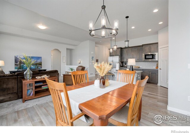 dining space featuring light wood-type flooring, a chandelier, and sink