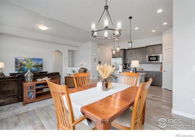 dining space featuring baseboards, an inviting chandelier, recessed lighting, arched walkways, and light wood-type flooring