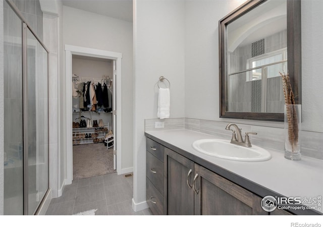 bathroom with vanity, a spacious closet, and a stall shower