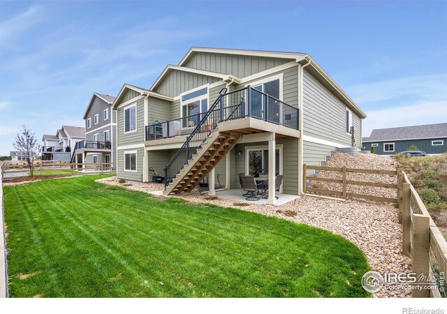 rear view of property with a patio, a lawn, and a deck