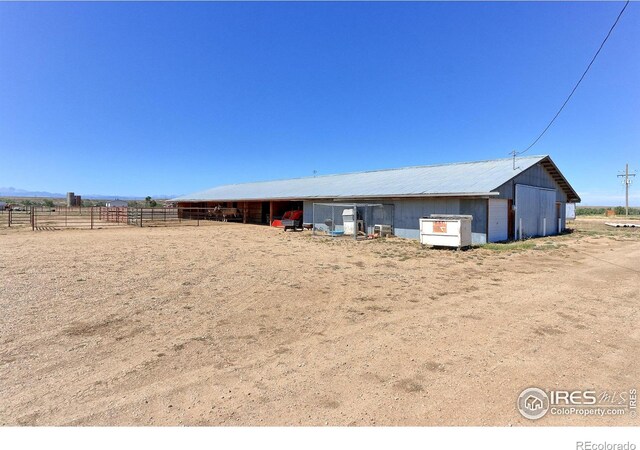 view of pole building with fence and a rural view