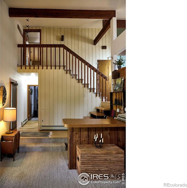 staircase featuring a towering ceiling, hardwood / wood-style flooring, wood walls, and beam ceiling