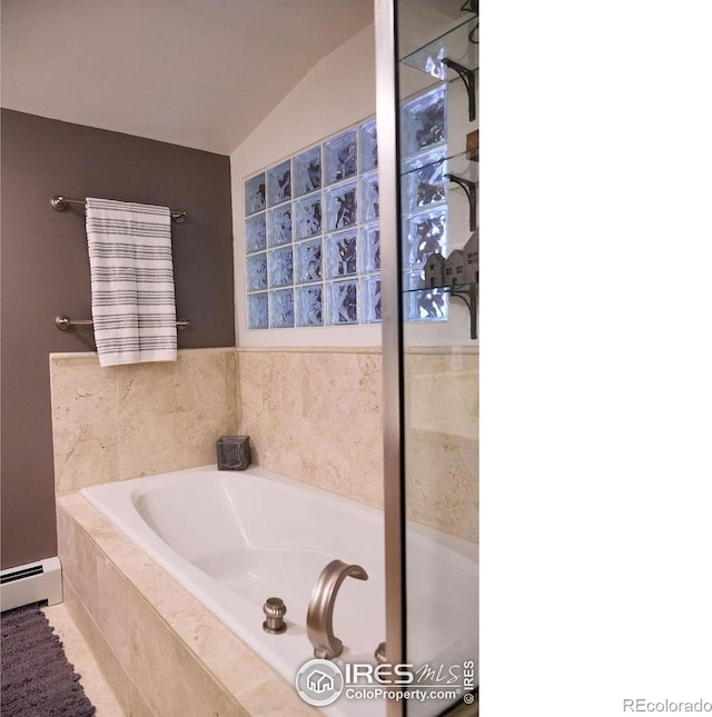 bathroom featuring lofted ceiling, baseboard heating, and tiled tub