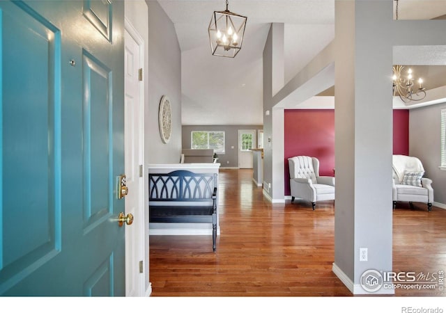 foyer with an inviting chandelier, vaulted ceiling, a textured ceiling, and hardwood / wood-style flooring