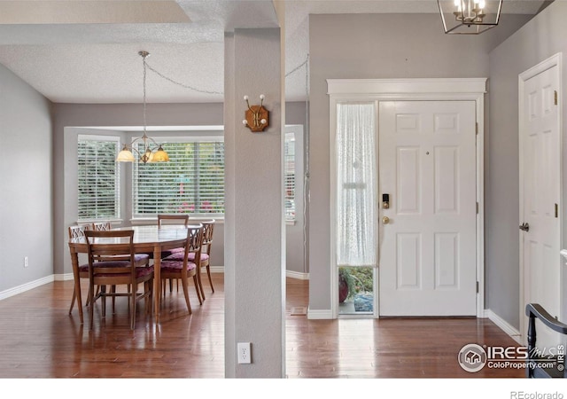 foyer entrance with an inviting chandelier, dark hardwood / wood-style floors, and a textured ceiling