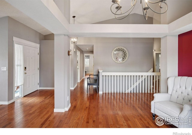 interior space with an inviting chandelier, wood-type flooring, and vaulted ceiling