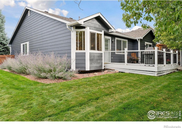 back of house featuring a lawn and a deck