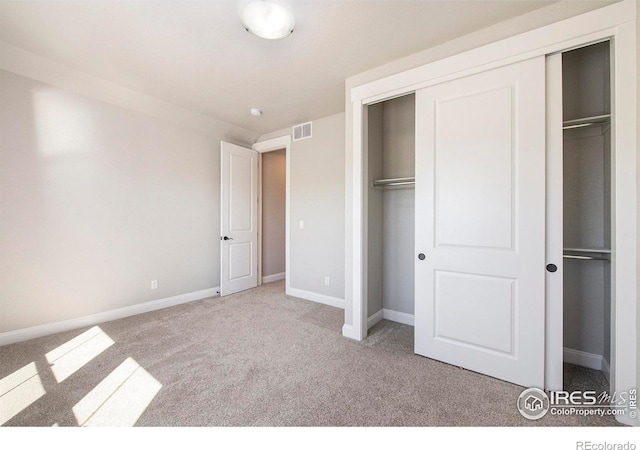 unfurnished bedroom with light carpet and a closet