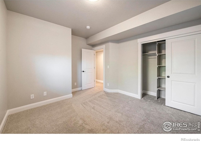 unfurnished bedroom with light colored carpet, a closet, and a textured ceiling