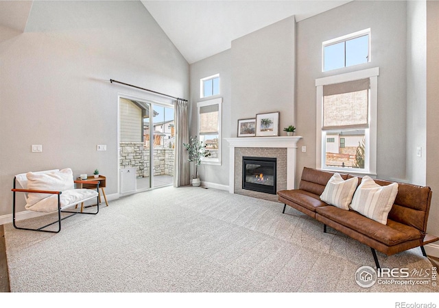 living room featuring carpet flooring, a tiled fireplace, and high vaulted ceiling