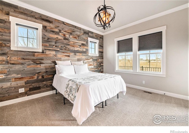 carpeted bedroom with crown molding, a chandelier, and wood walls