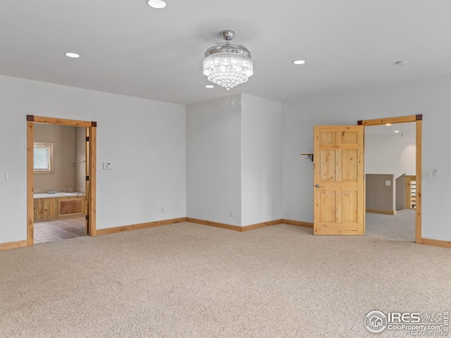 carpeted spare room featuring a chandelier