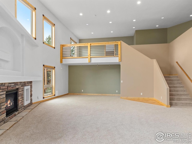 unfurnished living room with light carpet, a fireplace, and a high ceiling