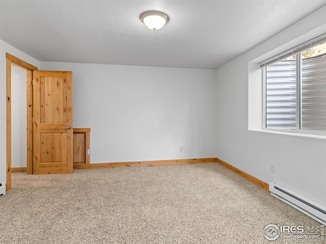 spare room with a textured ceiling, baseboard heating, and carpet flooring