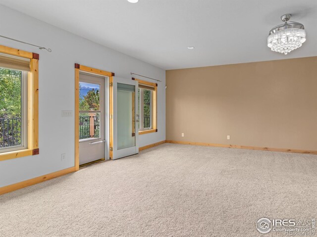 carpeted spare room with plenty of natural light and a chandelier